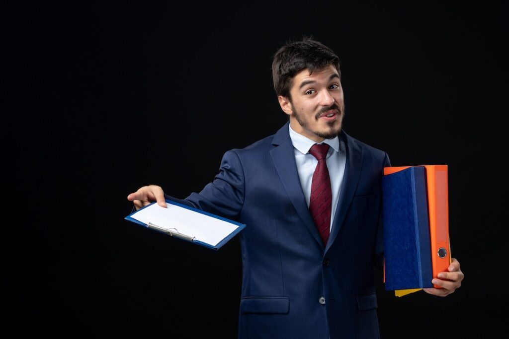 confident male suit holding several documents asking something isolated dark wall 140725 96983
